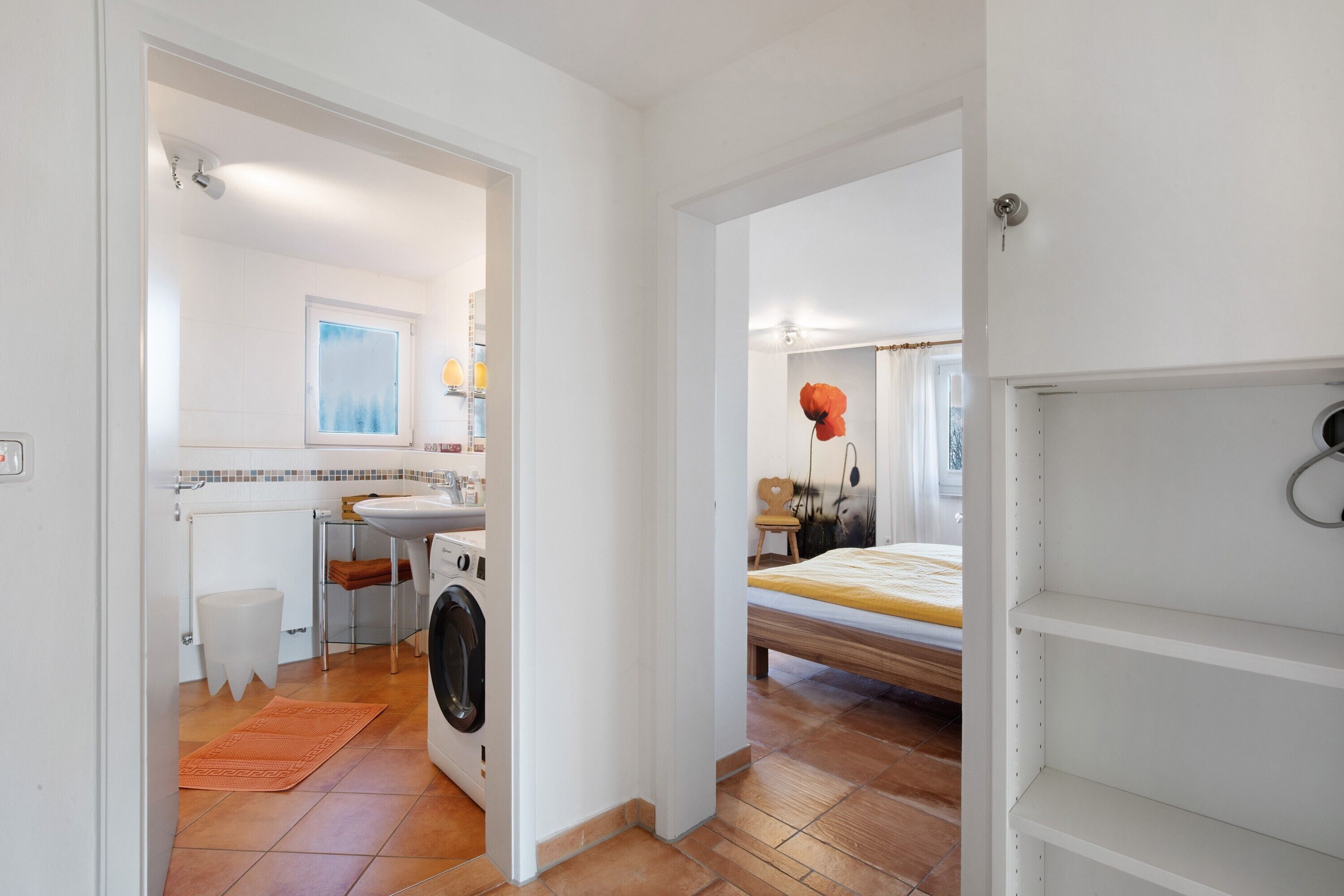 Una habitación compacta con cama, lavadora, lavabo y ventana.