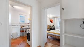Una habitación compacta con cama, lavadora, lavabo y ventana.