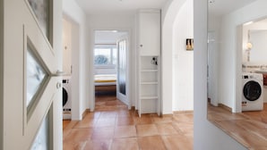 A hallway with a washing machine, a door with frosted glass, and a shelf unit. - Apartment 'Birkethof Teichblick' with Mountain View, Private Terrace, and Wi-Fi (Grimoldsried)