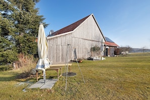Ein hölzernes Bauernhaus mit rotem Dach, einer Schaukel und einem Picknicktisch in einer grünen Wiese.