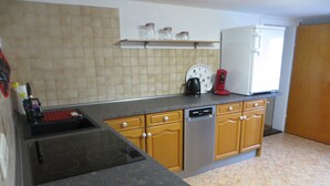 A kitchen with a stove, dishwasher, and a refrigerator. There are cabinets and a countertop.