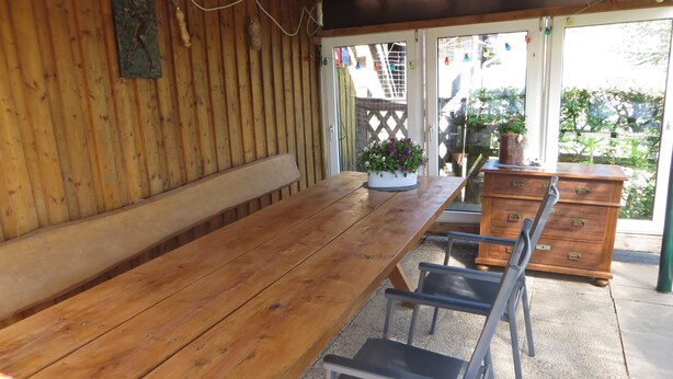 A wooden table with benches, a dresser, and a potted plant.
