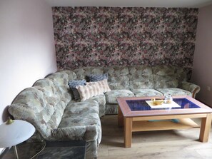 A living room with a floral-patterned sofa, a wooden coffee table, and a small side table.