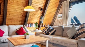 Una habitación acogedora con techo de madera, un sofá, una mesa y un farol colgante.