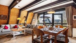 Una habitación acogedora con techo de madera, una mesa de comedor con sillas, un sofá y un ventanal grande.
