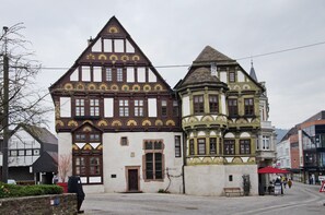 A traditional half-timbered building with a prominent tower, a stone wall, and a bench. - Holiday Home 'Haus Unterm Räuschenberg' with Mountain View, Private Terrace & Wi-Fi (Höxter)