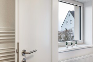 A white door with a window, a radiator, and three small potted plants on the windowsill. - Haus Fuldablick 'Room 1' with Shared Garden and Wi-Fi (Rotenburg an der Fulda)