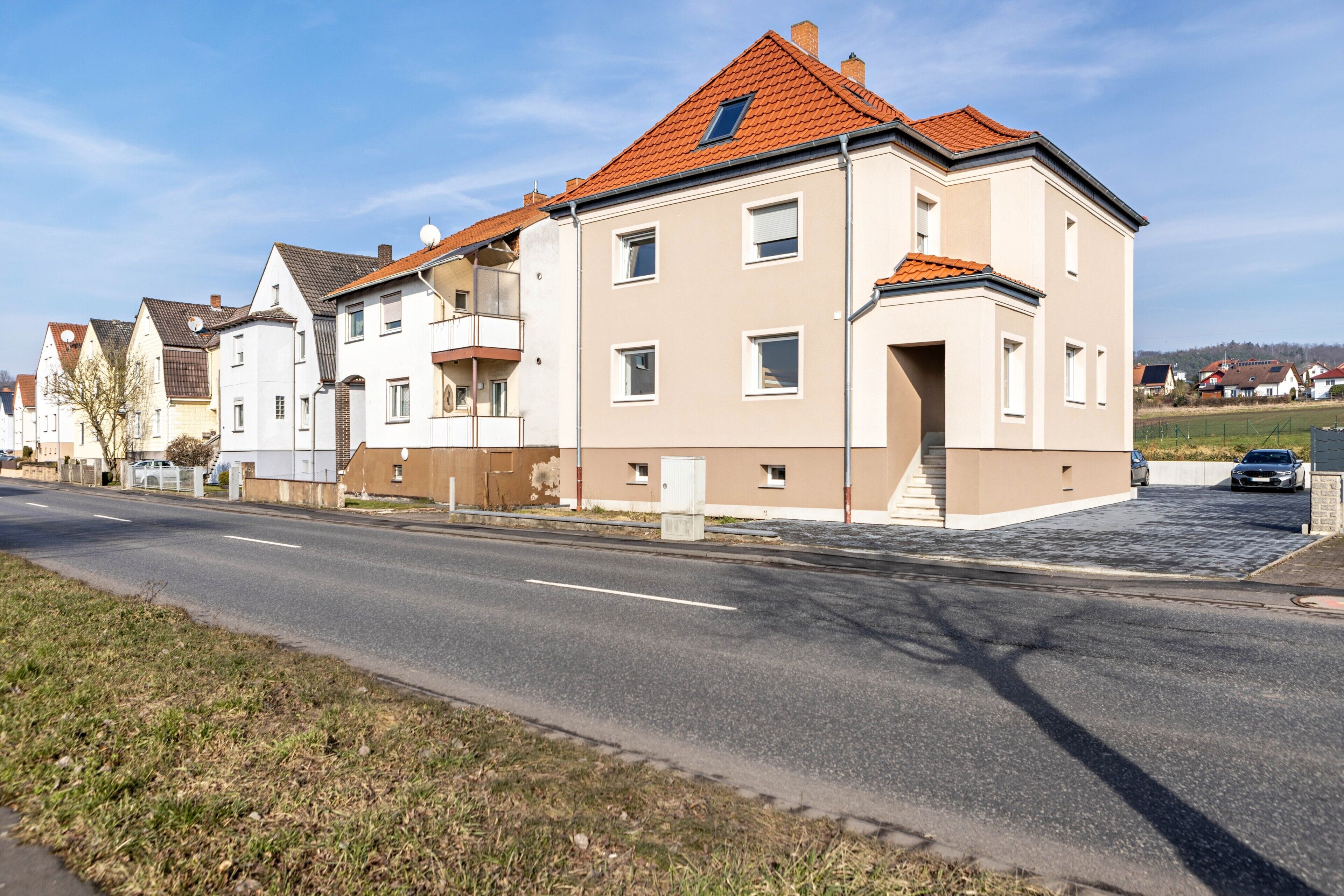 A residential street with modern houses, a clear sky, and a well-maintained road.