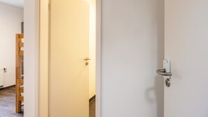 A hallway with a wooden ladder, a white door with a key lock, and a light fixture on the ceiling. - Haus Fuldablick 'Room 2' with Shared Garden and Wi-Fi (Rotenburg an der Fulda)
