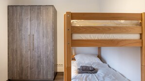 A bunk bed with white bedding and a wooden headboard, a wardrobe with a grey finish, and a wooden floor. - Haus Fuldablick 'Room 2' with Shared Garden and Wi-Fi (Rotenburg an der Fulda)