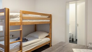 A bunk bed with a wooden frame, a small table with papers, and a door leading to a bathroom. - Haus Fuldablick Room '4' with Shared Garden and Wi-Fi (Rotenburg an der Fulda)