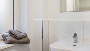 A bathroom with a white sink, a mirror above it, and a towel on a shelf. - Haus Fuldablick Room '4' with Shared Garden and Wi-Fi (Rotenburg an der Fulda)