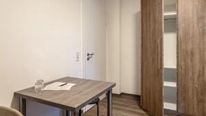 A room with a wooden wardrobe, a table with a pen and glasses, and a white door. - Haus Fuldablick Room '4' with Shared Garden and Wi-Fi (Rotenburg an der Fulda)