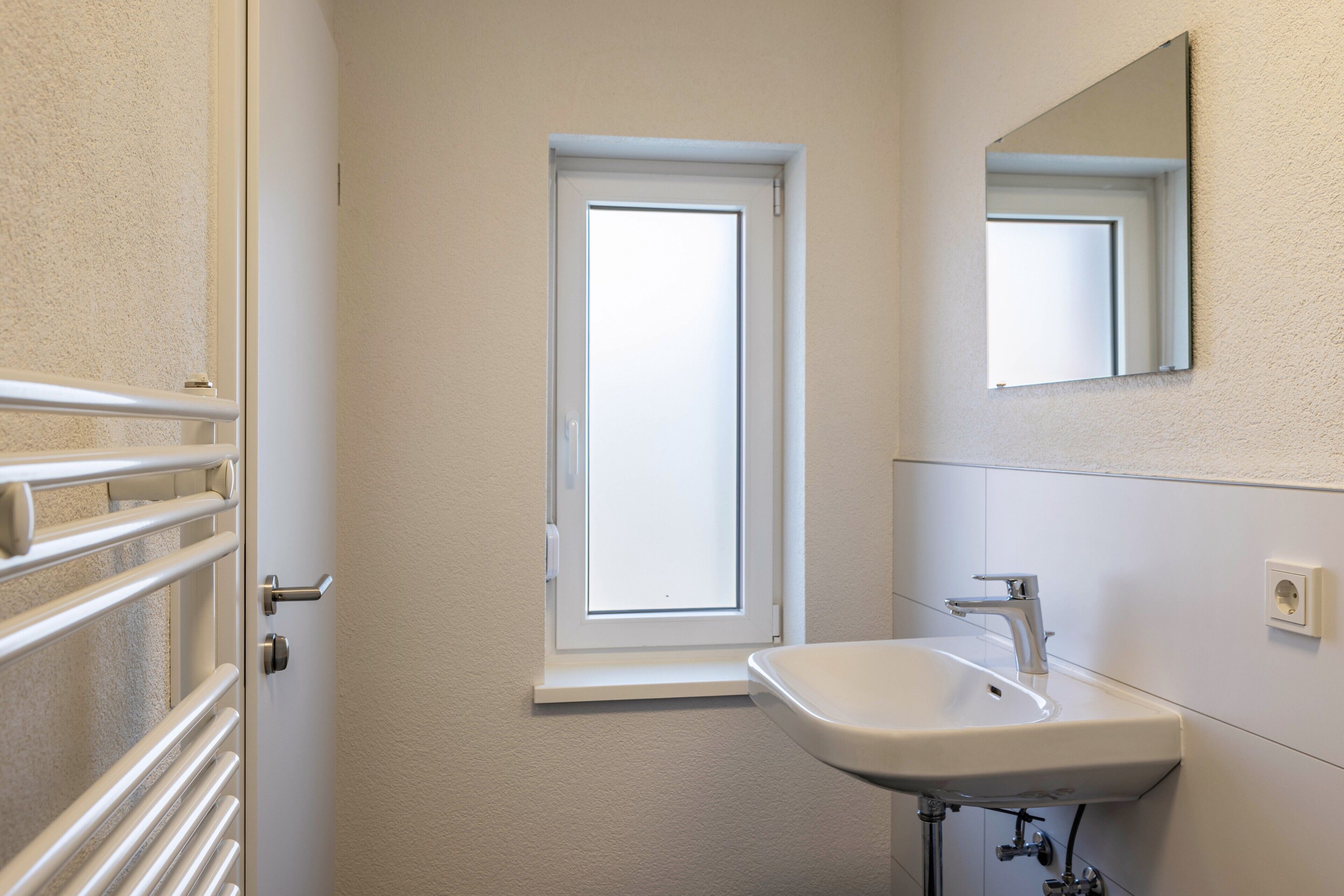 A bathroom with a window, a sink, and a mirror.