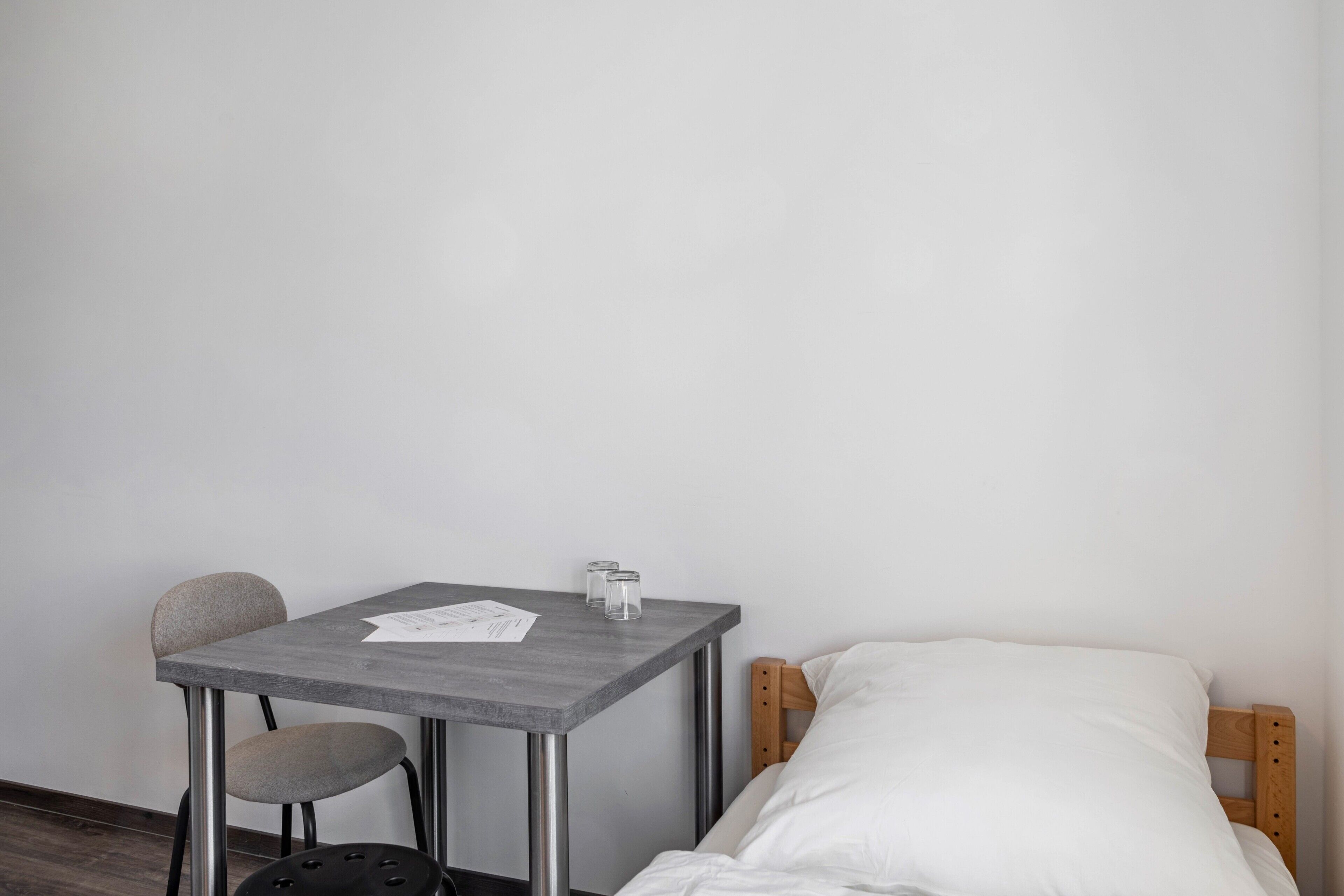 A small room with a single bed, a table, and a chair.