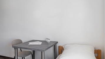 A small room with a single bed, a table, and a chair.