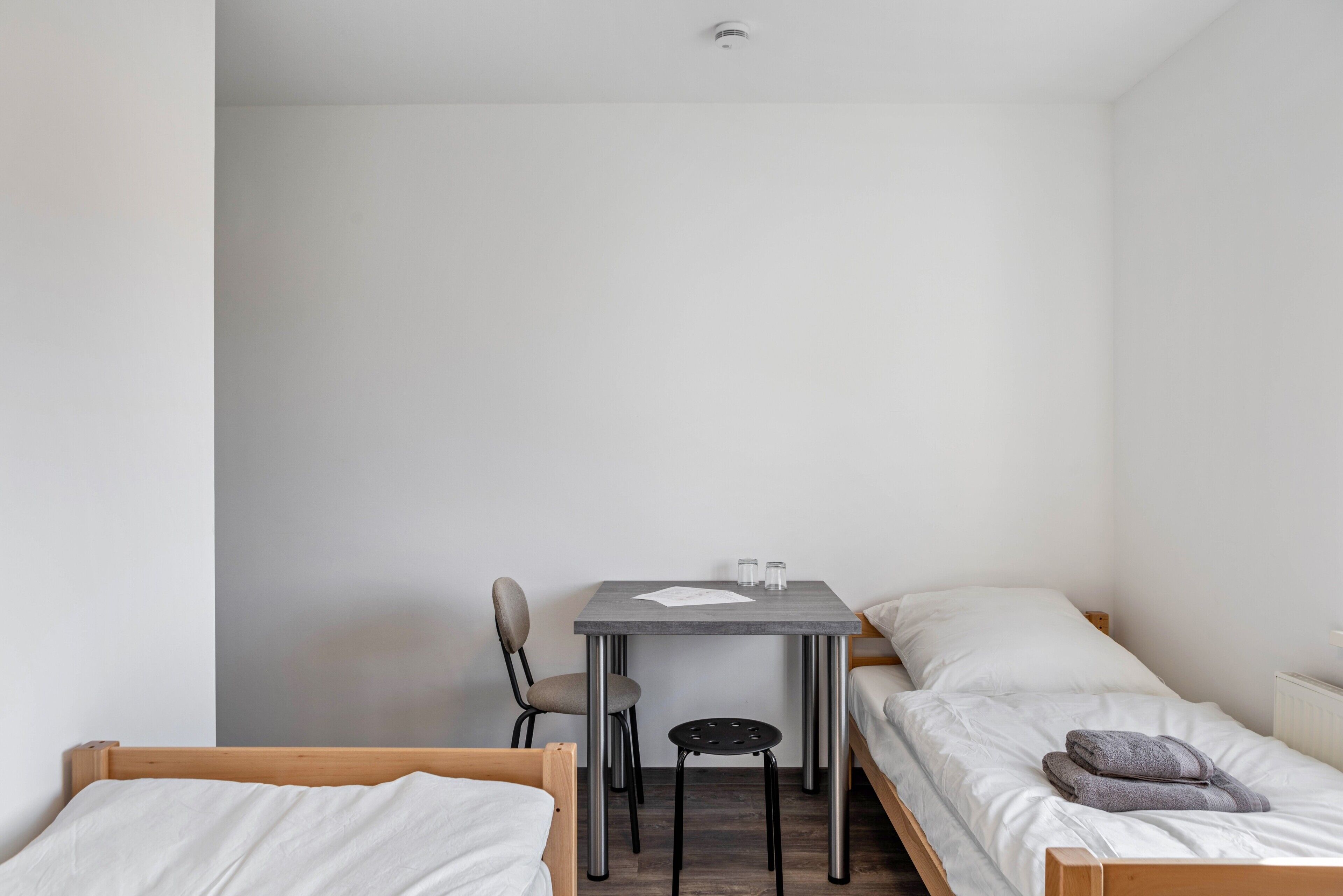 Eine kleine, einfache Unterkunft mit einem Bett, einem Schreibtisch und einem Stuhl.