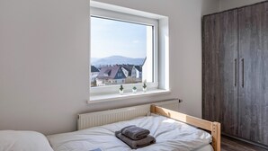 A bedroom with a bed, a window with a view of houses, a radiator, and a wardrobe. - Haus Fuldablick 'Room 6' with Shared Garden and Wi-Fi (Rotenburg an der Fulda)