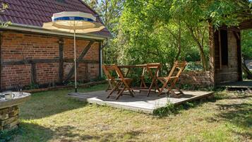 Ein Backsteinhaus mit rotem Dach, einem Holztisch und -stühlen sowie einer Terrasse.