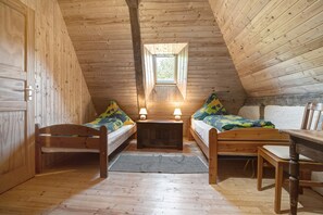Una habitación de madera con dos camas, una mesita y una ventana.