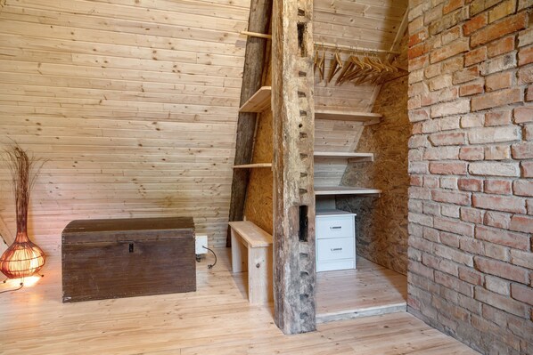A wooden interior with a loft area, a brick wall, and a hanging rack.