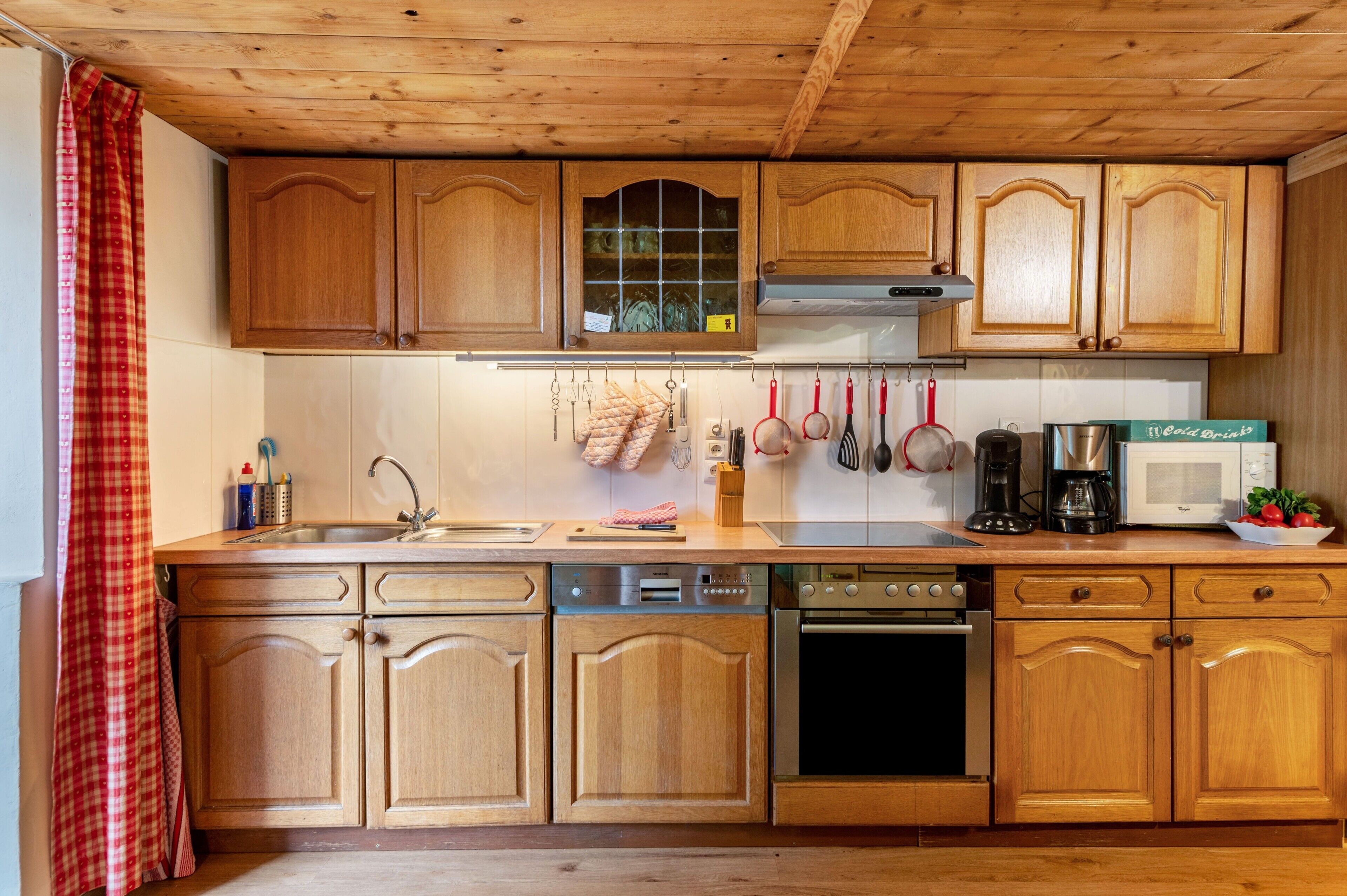 A kitchen with wooden cabinets, a stainless steel sink, a microwave, and a coffee maker.