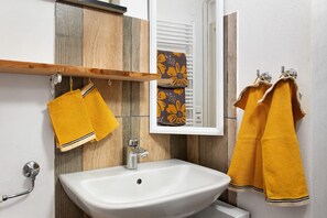 A bathroom with a white sink, wooden panel wall, and yellow towels. - Apartment 'Zizi' with Mountain View, Private Terrace and Wi-Fi (Stockach)