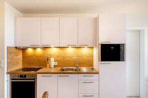 Een moderne keuken met witte kastjes, een roestvrijstalen spoelbak en een inbouwoven.