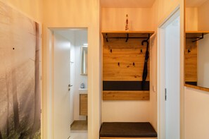 A hallway with a wooden bench, a coat rack, and a mirror on the wall. - Apartment 'Wolke8' with Private Sauna, Stunning Mountain Views, Balcony, Wi-Fi, Parking (Goslar-Hahnenklee)