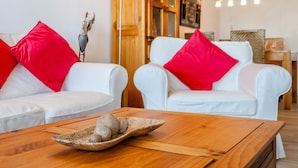 A room with two white sofas, each with a red pillow, and a wooden coffee table with a decorative bowl. - Apartment 'Wolke8' with Private Sauna, Stunning Mountain Views, Balcony, Wi-Fi, Parking (Goslar-Hahnenklee)