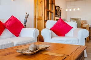 A room with two white sofas, each with a red pillow, and a wooden coffee table with a decorative bowl. - Apartment 'Wolke8' with Private Sauna, Stunning Mountain Views, Balcony, Wi-Fi, Parking (Goslar-Hahnenklee)