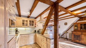 A kitchen with wooden beams, white cabinets, and a tiled floor.