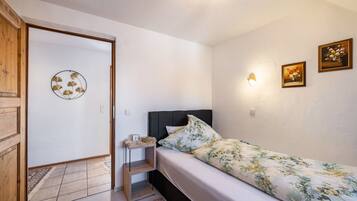 Ein Schlafzimmer mit einem Bett, einem Nachttisch, einer Wandlampe und zwei gerahmten Bildern.