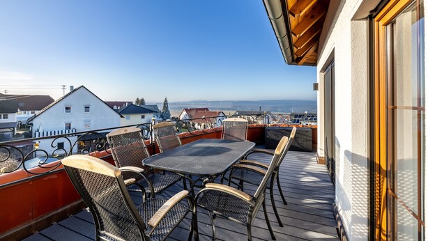 A balcony with a table and chairs, overlooking a town.