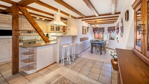 A kitchen with wooden beams, a bar area, and a dining space with chairs and a table.