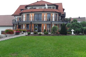 Een herenhuis met een balkon, een pannendak en een verzorgde tuin.