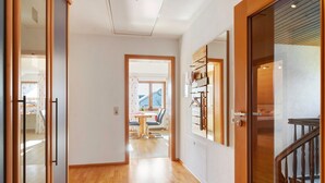 A hallway with wooden flooring, a dining area with a table and chairs, and a staircase with a wooden railing. - Apartment 'Haus Am Ettenberg' with Balcony and Wi-Fi (Frickingen)