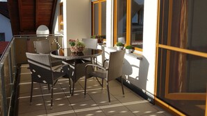 A balcony with wicker furniture, potted plants, and a view of the street. - Apartment 'Haus Am Ettenberg' with Balcony and Wi-Fi (Frickingen)