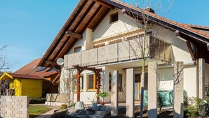 A two-story house with a sloped roof, a wooden pergola, and a stone pathway leading to the entrance. - Apartment 'Haus Am Ettenberg' with Balcony and Wi-Fi (Frickingen)