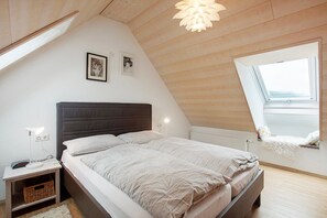 A bedroom with a bed, bedside table, lamp, and a window. - Apartment 'Hinz' with Mountain View, Balcony and Wi-Fi (Todtnau)