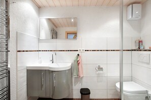 A bathroom with a sink, mirror, towel rack, toilet, and trash bin. - Apartment 'Hinz' with Mountain View, Balcony and Wi-Fi (Todtnau)