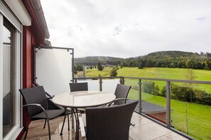 A balcony with a table and chairs, overlooking a green landscape and hills. - Apartment 'Hinz' with Mountain View, Balcony and Wi-Fi (Todtnau)