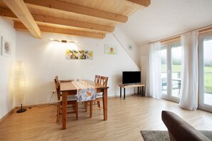 A dining area with a wooden table and chairs, a TV, and a view of the outdoors. - Apartment 'Hinz' with Mountain View, Balcony and Wi-Fi (Todtnau)