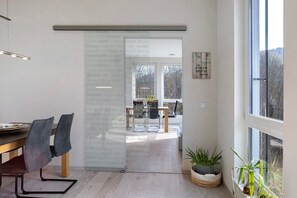 Un intérieur moderne comprenant un coin repas, une cloison en verre et une vue sur l’extérieur.