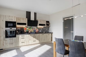 Une cuisine moderne avec des meubles en bois, une hotte noire et un bar pour prendre le petit-déjeuner.
