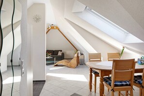 A modern interior with a dining area, a loft-style room, and a visible skylight.