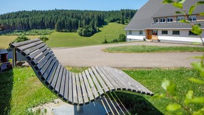 A bench in a grassy area with a house in the background.