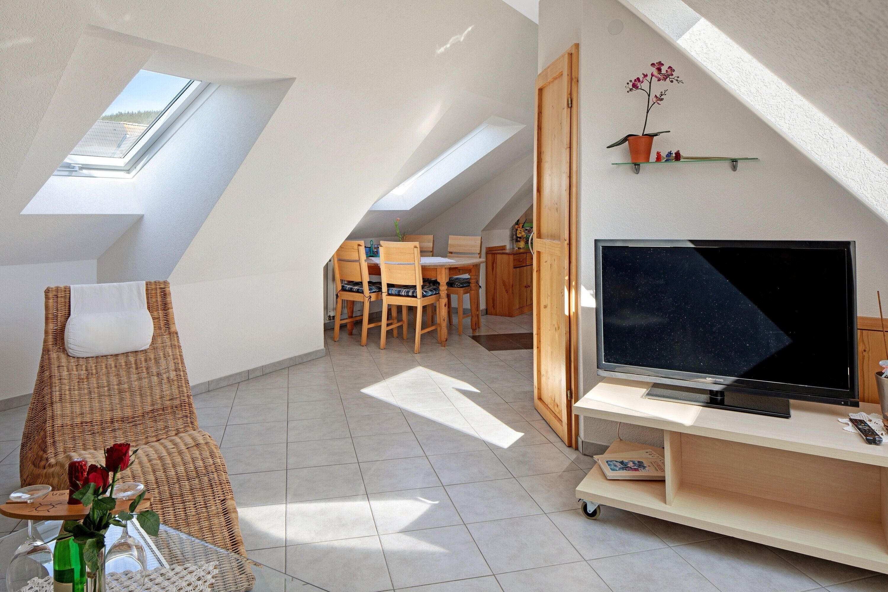 Une chambre de style loft moderne, dotée de fenêtres de toit, d’une télévision et d’un coin repas.
