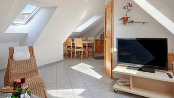 Une chambre de style loft moderne, dotée de fenêtres de toit, d’une télévision et d’un coin repas.