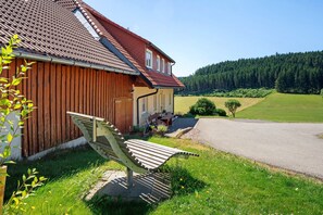 A house with a sloped roof, a wooden fence, and a bench outside.